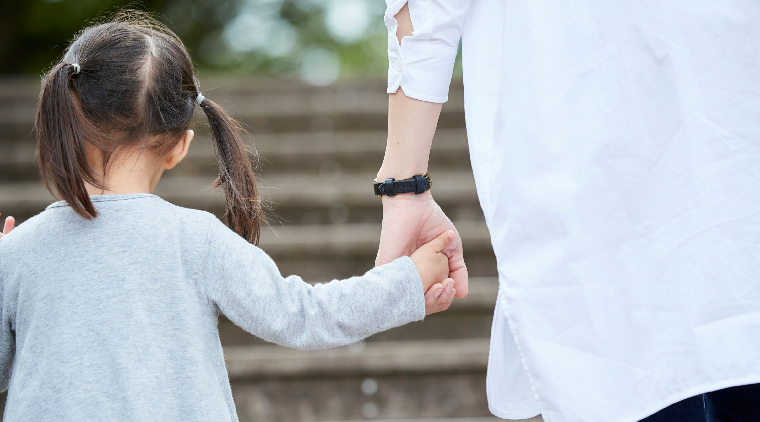 Adult woman holding the hand of a child.